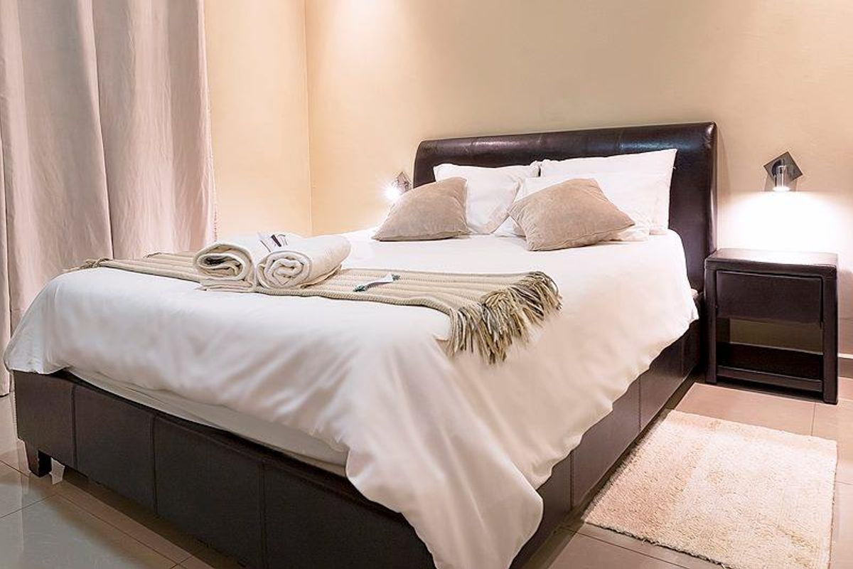A well-lit bedroom featuring tiled flooring and wall-mounted accent lighting.