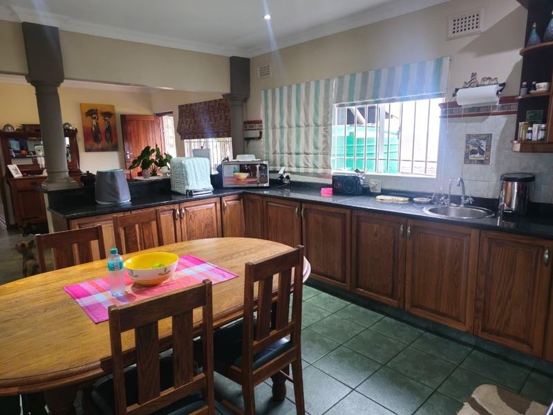 Open plan kitchen and dining area featuring wooden cabinetry, granite countertops, and tiled flooring, providing a functional space for cooking and family meals.