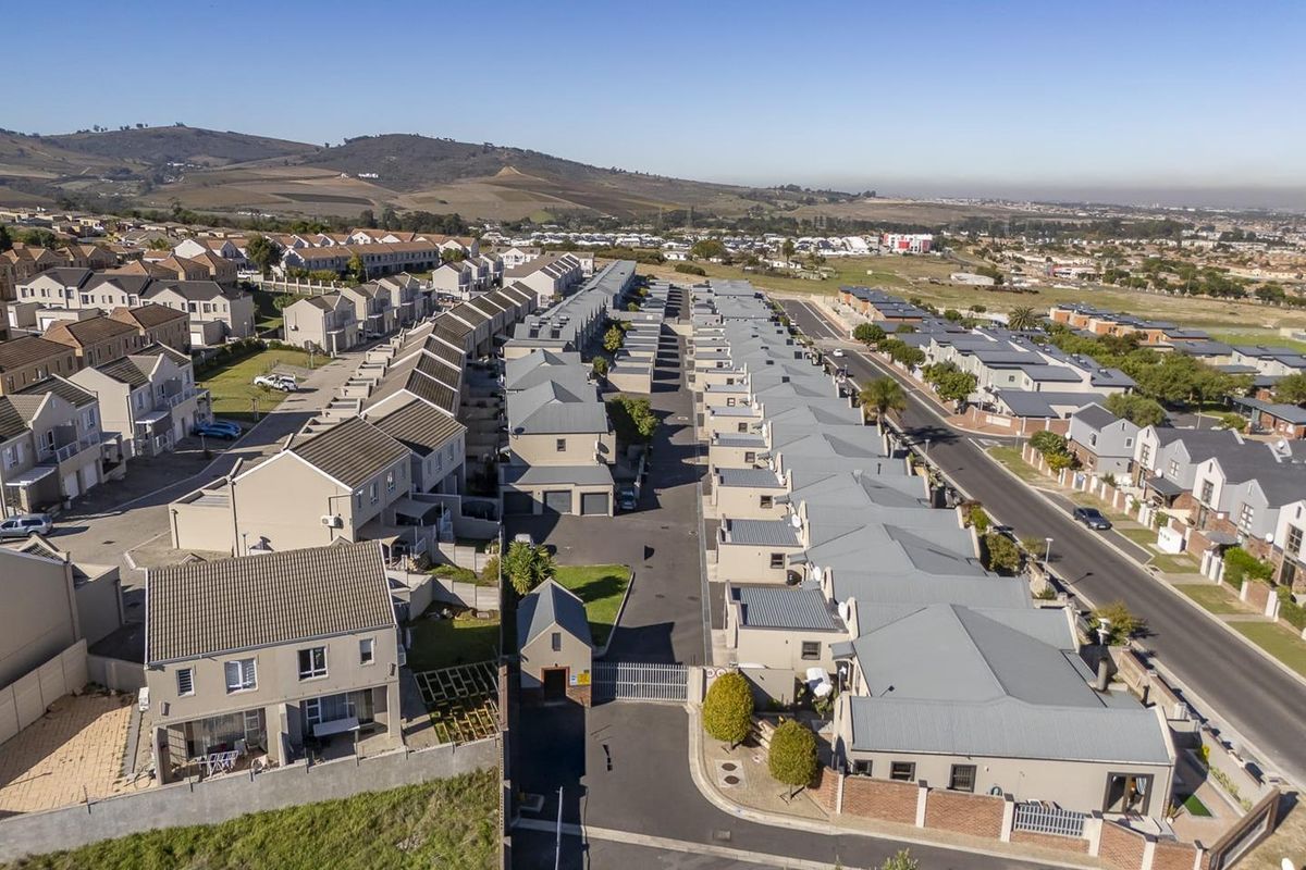 Aerial view of a residential apartment complex featuring uniform housing units, paved internal roads, and gated security access.