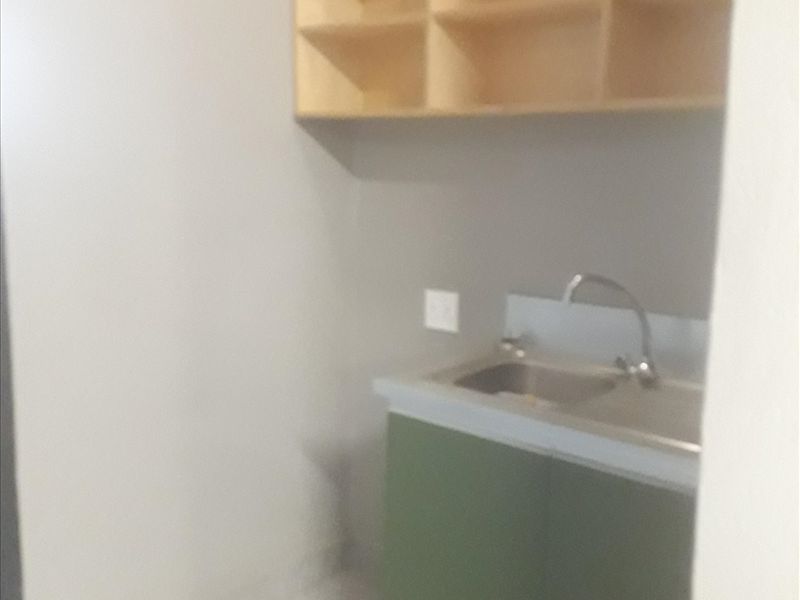 A functional scullery area featuring a stainless steel sink, built-in base cabinetry, and wall-mounted open shelving for storage.