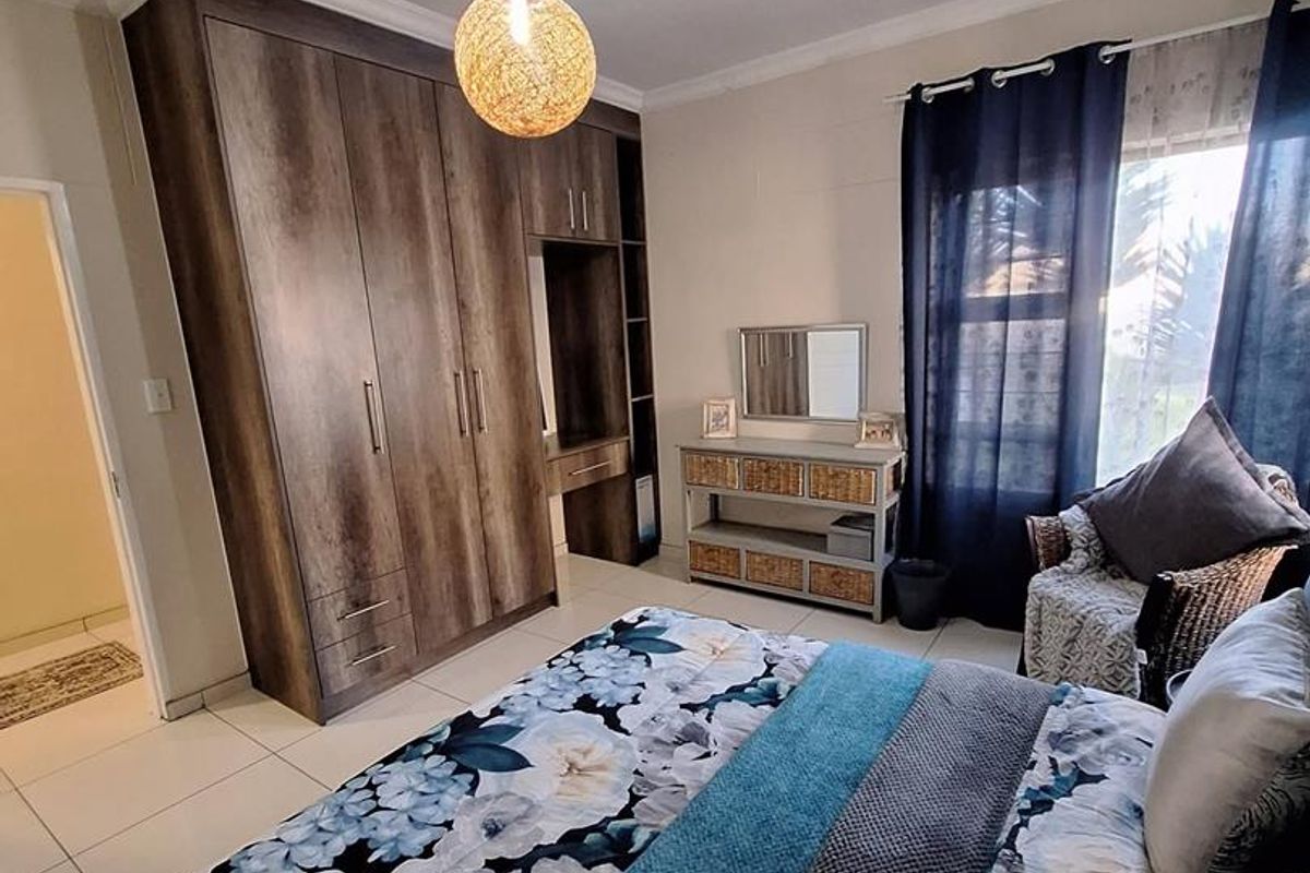 A well-maintained bedroom featuring built-in wooden cabinetry, tiled flooring, and a large window allowing natural light.