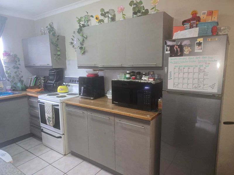 A functional kitchen featuring laminate countertops, built-in cabinetry, and tiled flooring, offering a practical layout with standard fixed appliances.