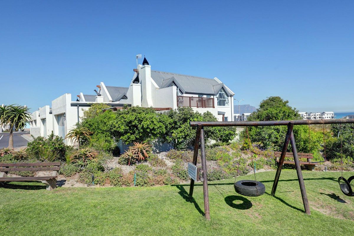 A view of the rear elevation of the townhouse, featuring a landscaped garden, balcony, and well-maintained exterior finishes.