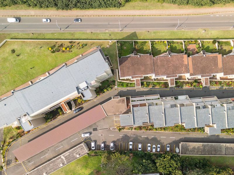 Aerial view of the townhouse complex showing building layouts, tiled roofs, parking areas, and surrounding landscaped grounds.