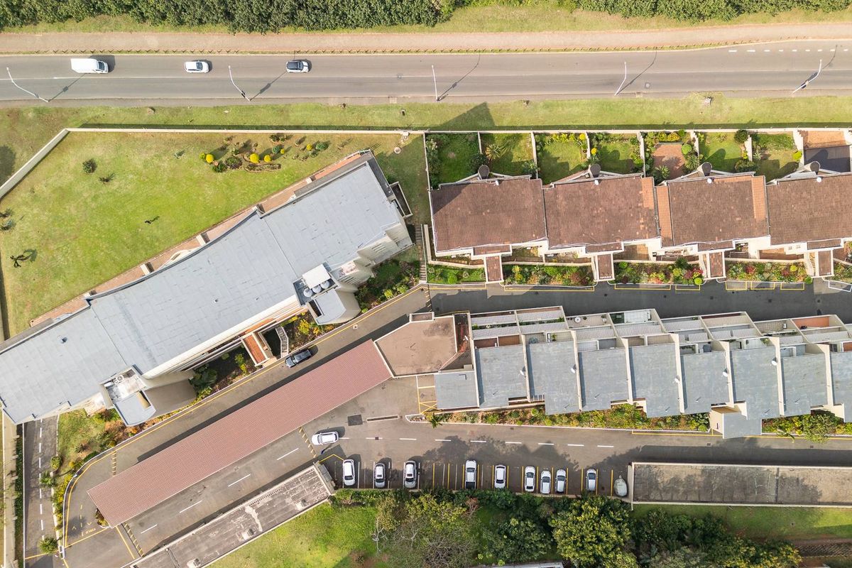 Aerial view of the townhouse complex showing building layouts, tiled roofs, parking areas, and surrounding landscaped grounds.