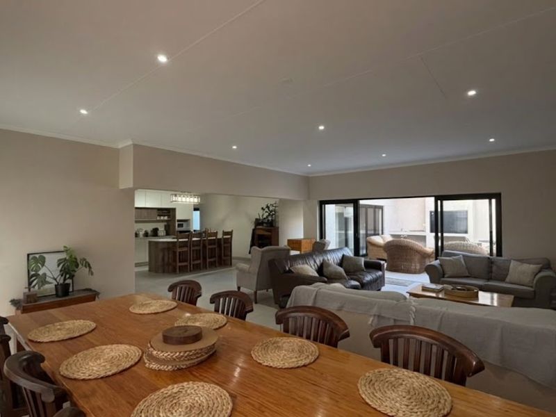 Spacious open-plan living and dining area featuring recessed lighting, tiled floors, and seamless flow to an outdoor patio through large sliding glass doors.