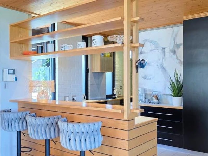 Modern kitchen featuring a timber breakfast bar, integrated cabinetry, and warm timber ceiling finishes, creating a functional and stylish culinary space.