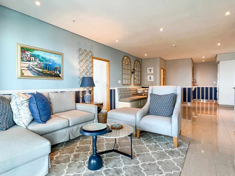 An open-plan living and dining area featuring polished tile flooring, recessed downlighting, and a built-in kitchen cabinetry unit.