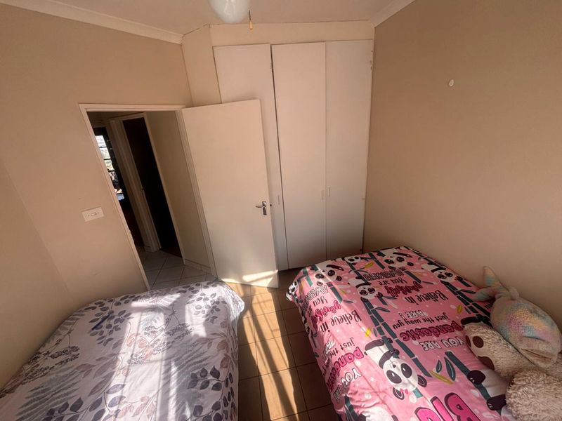A bedroom featuring built-in cupboards and neutral wall finishes, providing a functional space with direct access to the hallway.