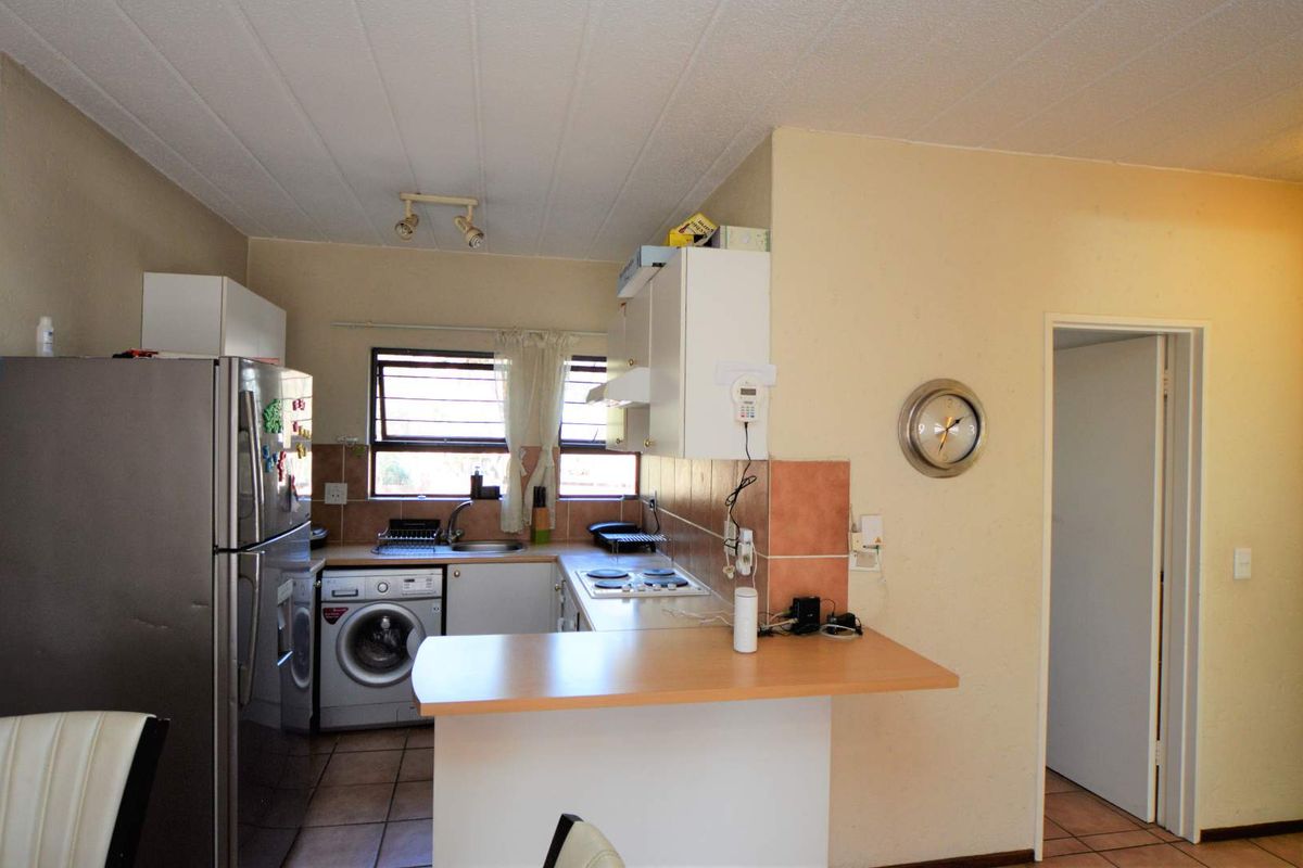 Compact kitchen featuring built-in cabinetry, laminate countertops, an electric hob, and integrated laundry plumbing, offering a functional layout for daily use.