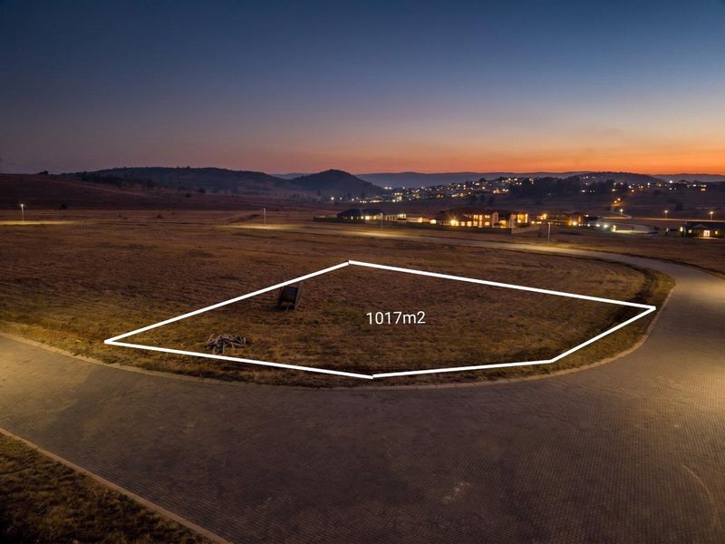 An aerial view of a 1017m2 vacant residential plot situated in a developed estate with paved road access and street lighting.