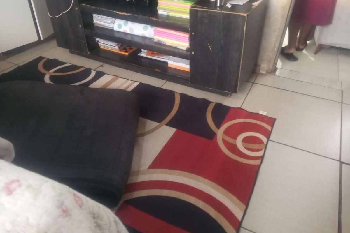 A view of a tiled living area floor with visible wear and tear, showing the transition between living space and an adjacent room.