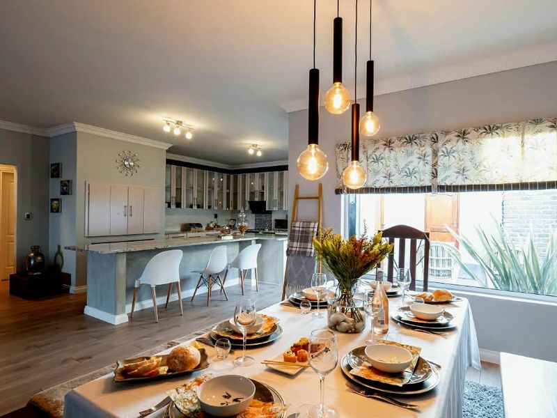 Spacious open-plan dining and kitchen area featuring a large island, modern pendant lighting, and neutral finishes, ideal for entertaining.