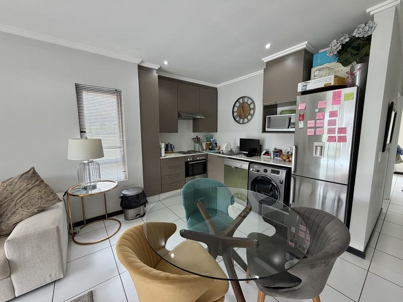 Open-plan kitchen and dining area featuring modern cabinetry, integrated appliances, tiled flooring, and neutral finishes, creating a functional and cohesive living space.