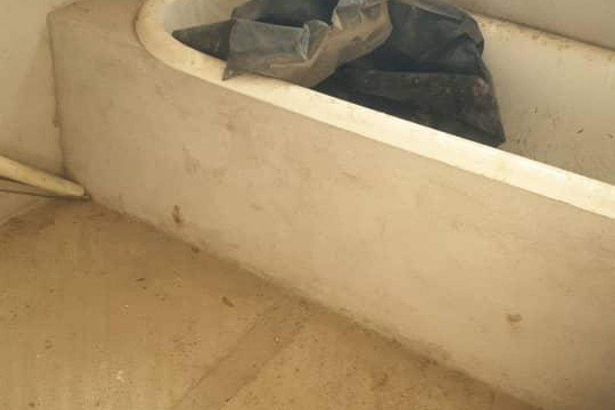 A bathroom in the early stages of construction, featuring a built-in bathtub and unfinished wall and floor surfaces.