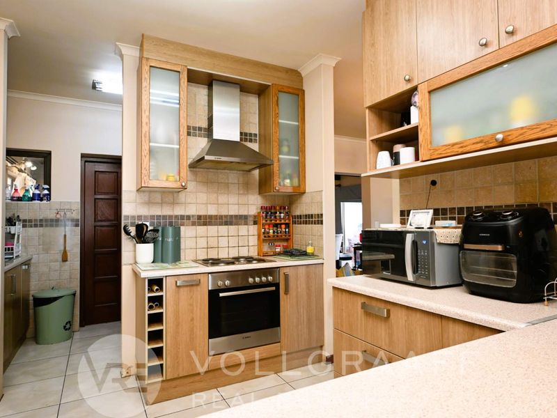 A functional kitchen featuring wood-finish cabinetry, tiled backsplash, built-in oven with extractor fan, and durable laminate countertops.
