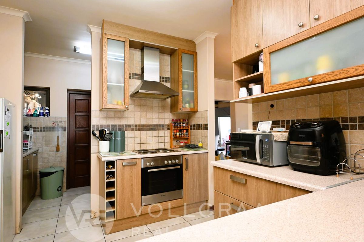 A functional kitchen featuring wood-finish cabinetry, tiled backsplash, built-in oven with extractor fan, and durable laminate countertops.