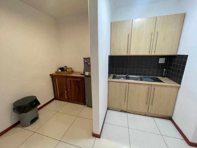 A functional scullery area featuring built-in cabinetry, a stainless steel sink, and tiled finishes, providing additional prep and wash-up space.