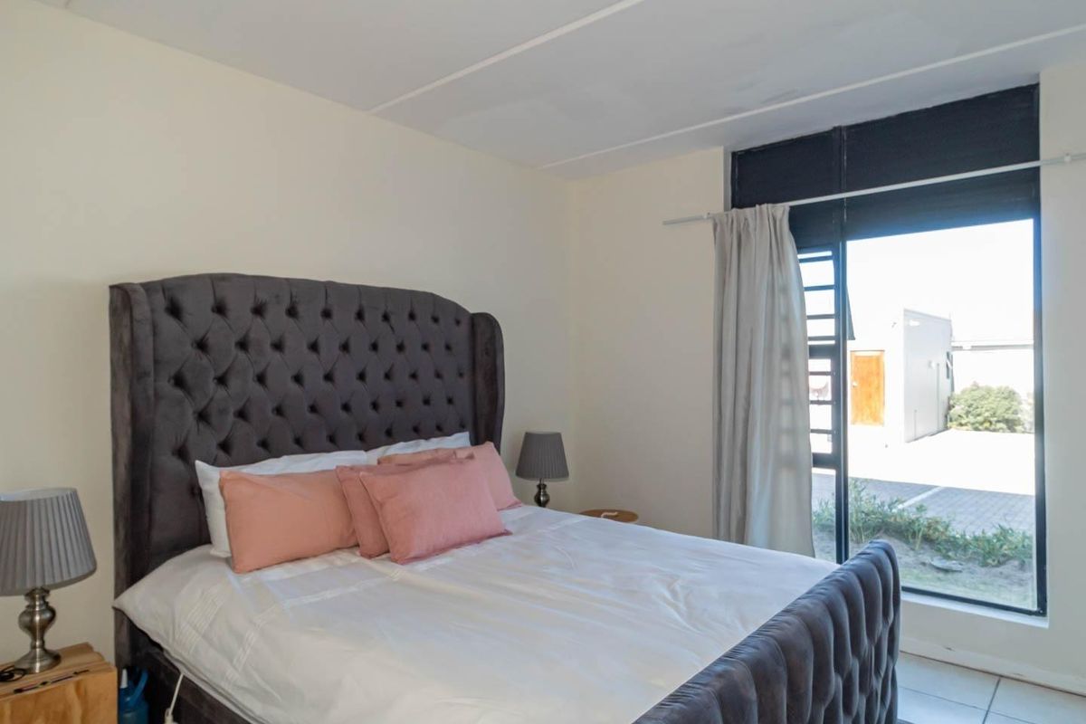 A bedroom featuring tiled flooring and a large window providing natural light and access to the exterior.