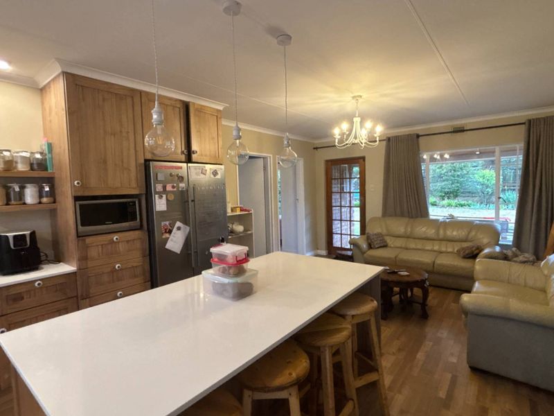 Open-plan living area featuring a modern kitchen with a central island, quartz countertops, timber cabinetry, and direct access to the outdoor space.