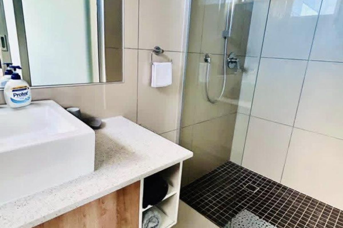 Modern bathroom featuring a vessel sink on a stone-topped vanity cabinet and a spacious walk-in shower with glass screen and tiled finishes.