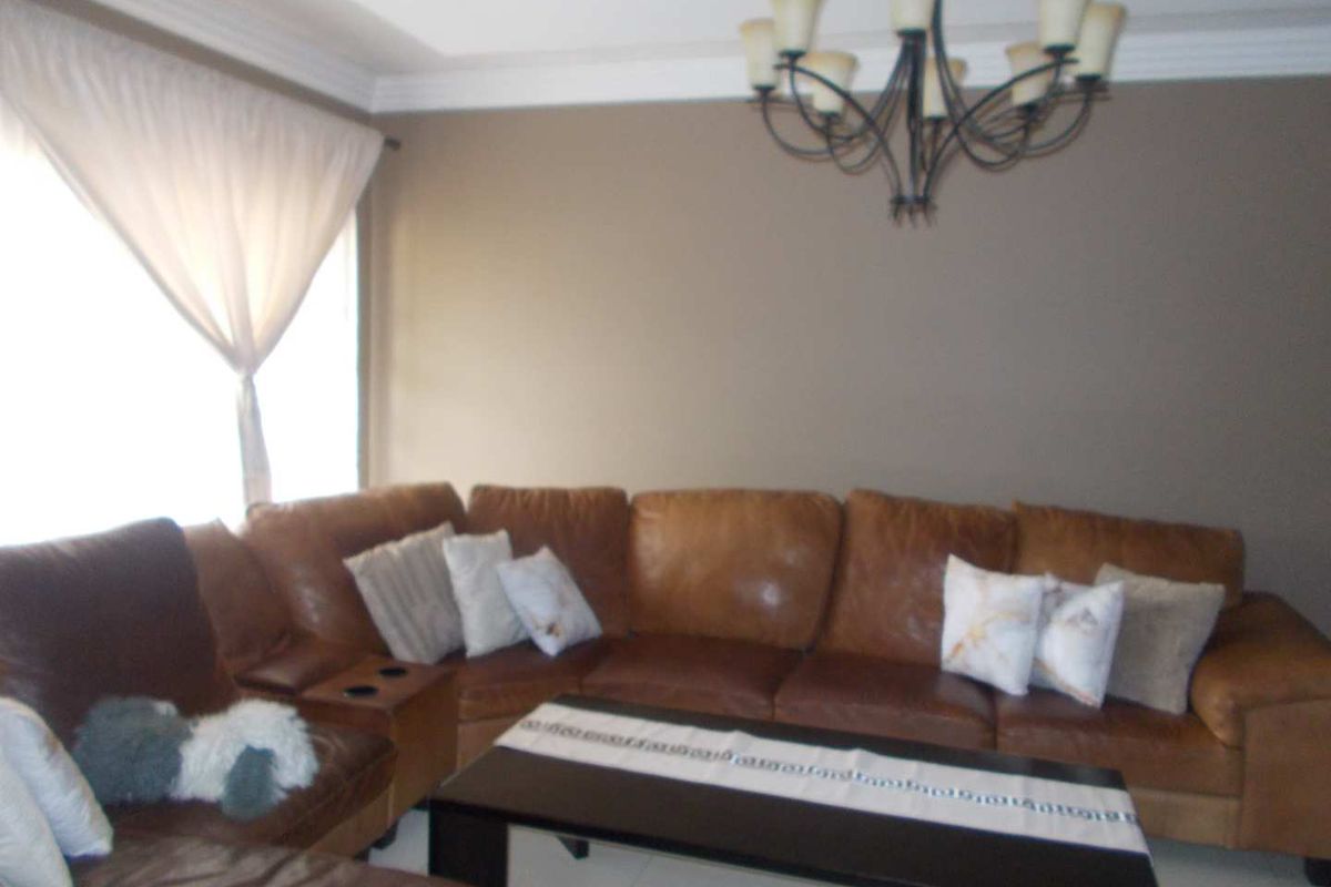A comfortable living room featuring neutral wall tones, tiled flooring, and a decorative ceiling chandelier.
