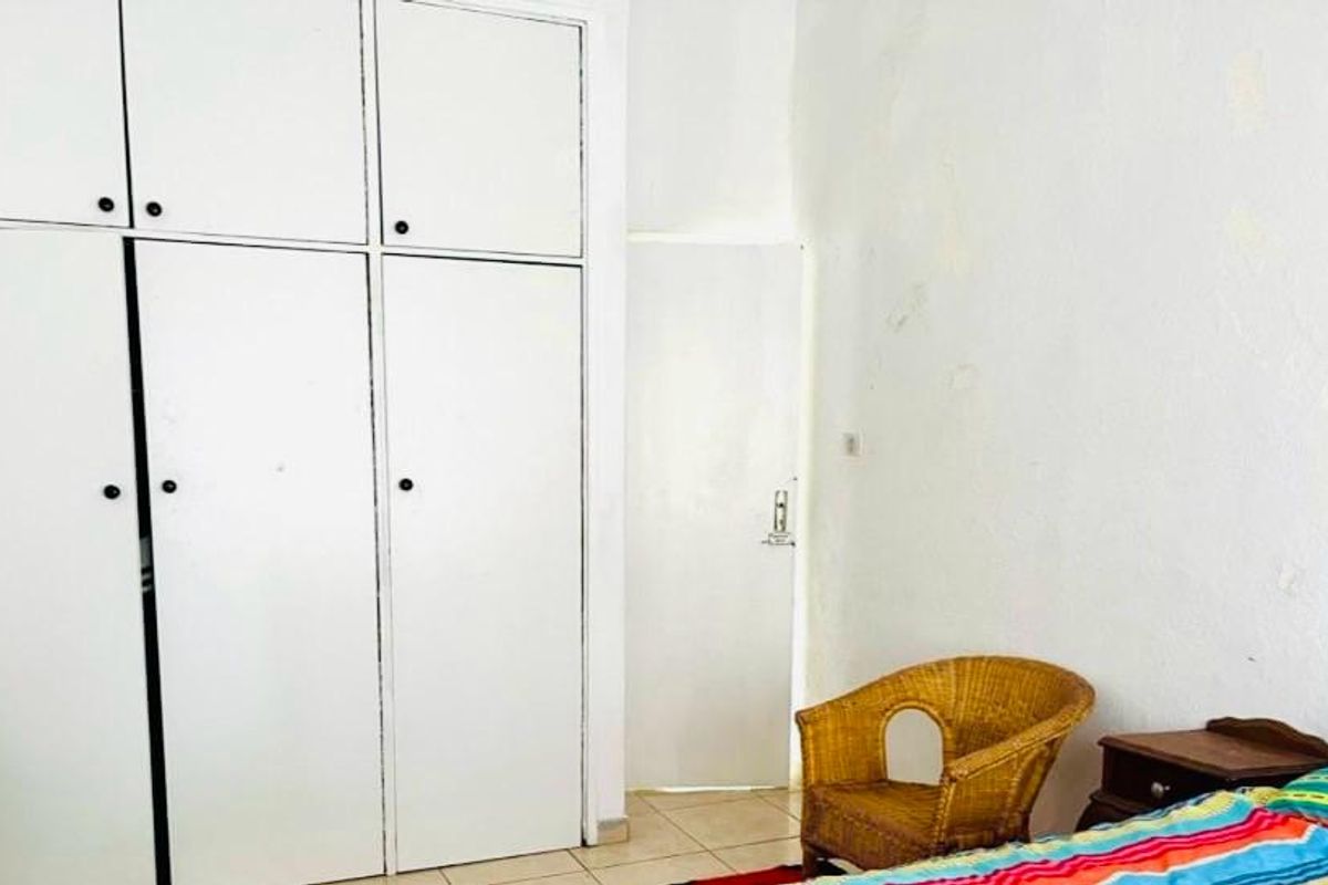 Bedroom featuring built-in white cabinetry and tiled flooring, offering functional storage space with potential for cosmetic updates to the wall finishes.