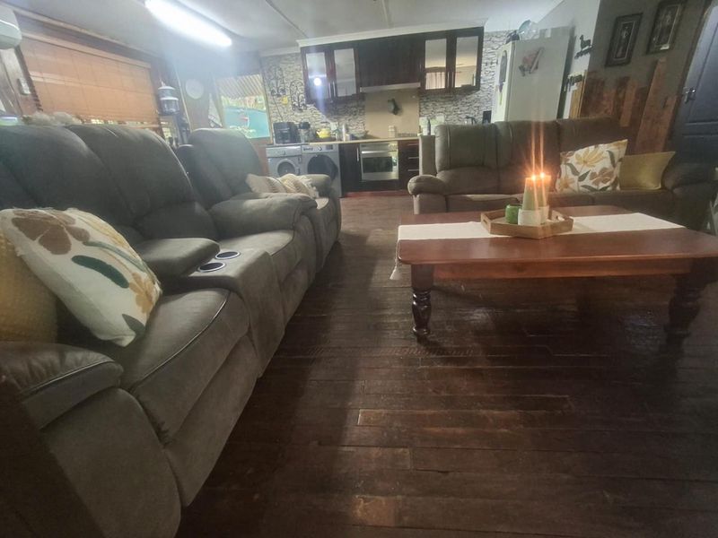 Open plan living area featuring dark timber flooring and a functional kitchen with built-in cabinetry, oven, and extractor fan.