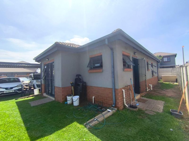 Rear view of the property featuring a combination of brick and plastered wall finishes, security gates, and functional top-hung windows.