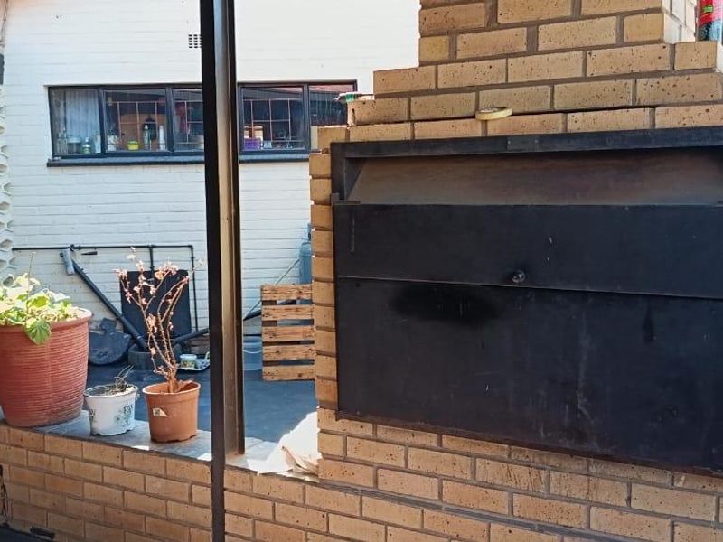 Outdoor patio area featuring a built-in brick braai and decorative breeze block wall, providing a functional space for outdoor entertaining.