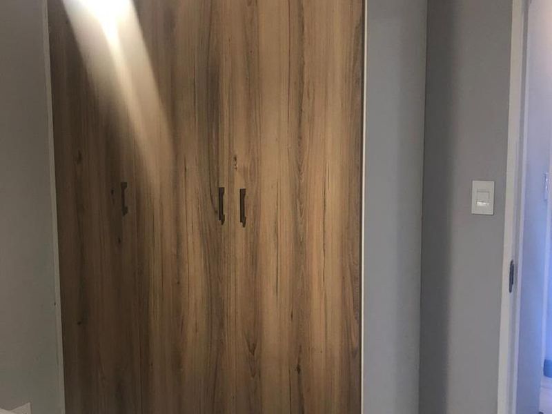 Bedroom featuring a modern wood-finish built-in wardrobe, tiled flooring, and neutral wall tones.