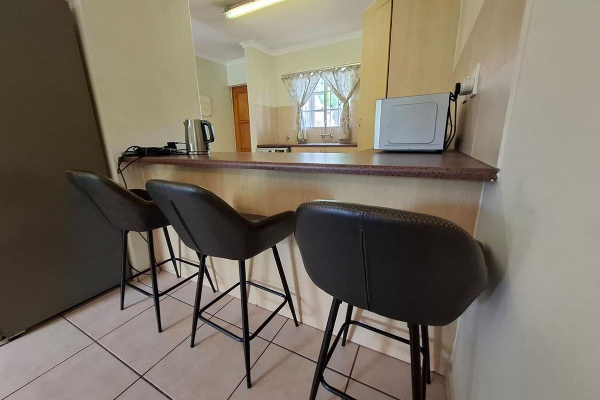 A functional kitchen featuring a breakfast bar counter, tiled flooring, and built-in cabinetry, providing a practical layout for daily meal preparation.