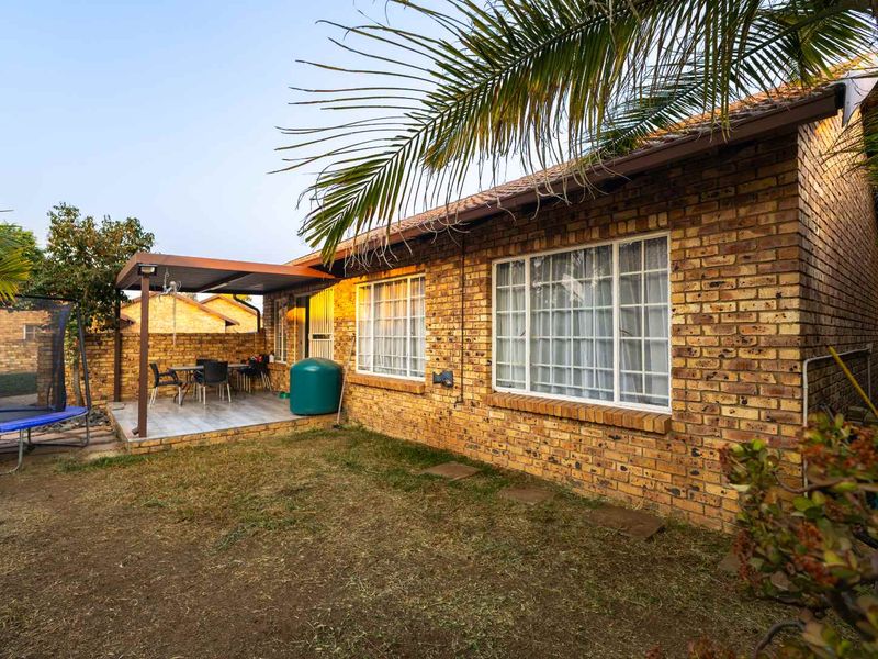 Rear view of a face brick townhouse featuring a covered patio area and a private garden space.