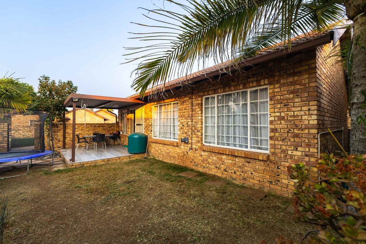 Rear view of a face brick townhouse featuring a covered patio area and a private garden space.