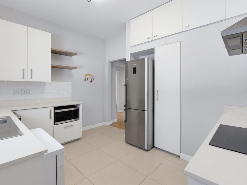 Modern kitchen featuring white cabinetry, stone countertops, subway tile backsplash, integrated appliances, and tiled flooring.