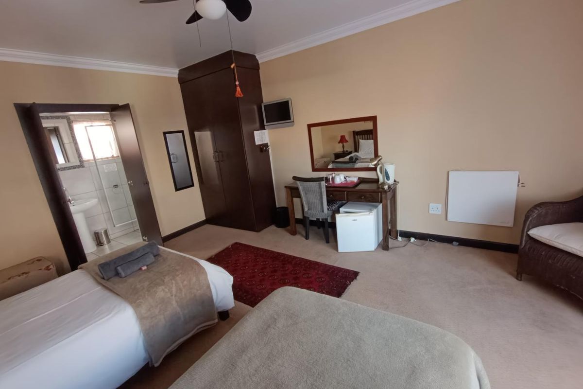 A bedroom featuring built-in cabinetry, a ceiling fan, and an en-suite bathroom with a pedestal basin.
