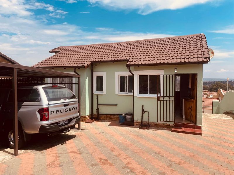 Front exterior view of the house featuring a tiled roof, paved driveway, and a covered carport area.