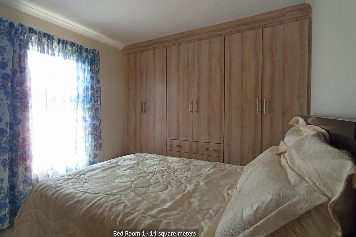 A bedroom featuring built-in wooden cabinetry and a window with curtains.