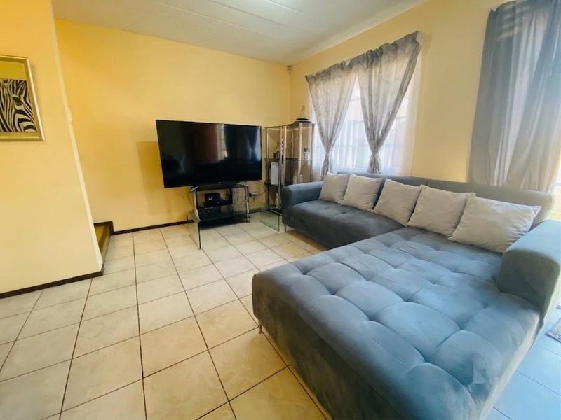 A living room featuring tiled flooring and a coved ceiling, providing a functional and neutral space for relaxation.