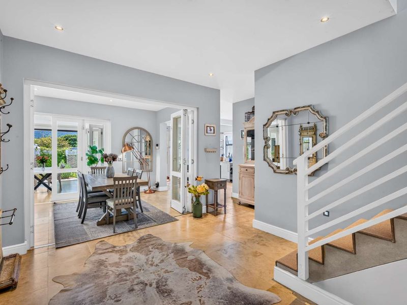 Open plan living and dining area featuring tiled flooring, recessed lighting, and a staircase with a white balustrade leading to the upper level.