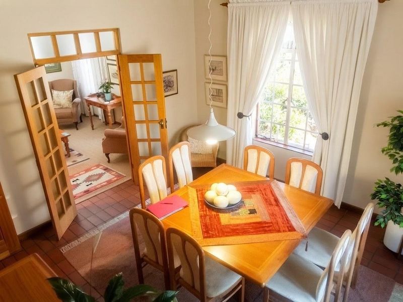 A bright dining room featuring tiled flooring, a pendant light, and classic wooden French doors leading into an adjacent living space.