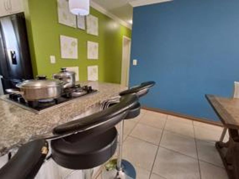 Open plan kitchen and dining area featuring granite countertops, a gas hob, and tiled flooring with vibrant accent walls.