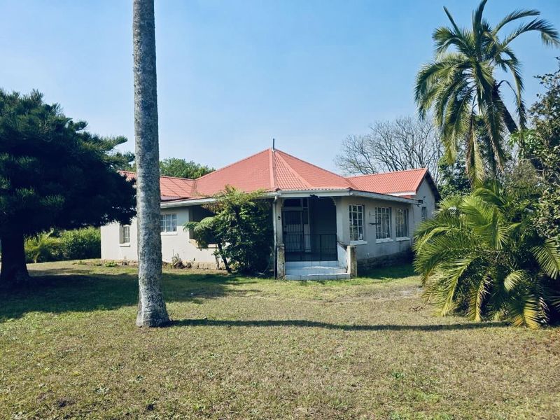 A single-story residential house featuring a red tiled roof, covered entrance porch, and established garden surroundings.