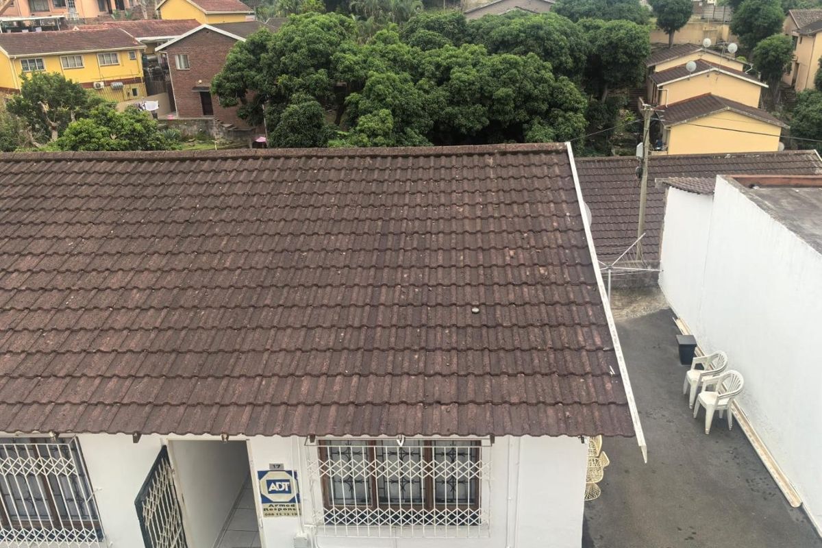 An elevated view of the townhouse property, showcasing the tiled roof, security features, and surrounding residential neighborhood.