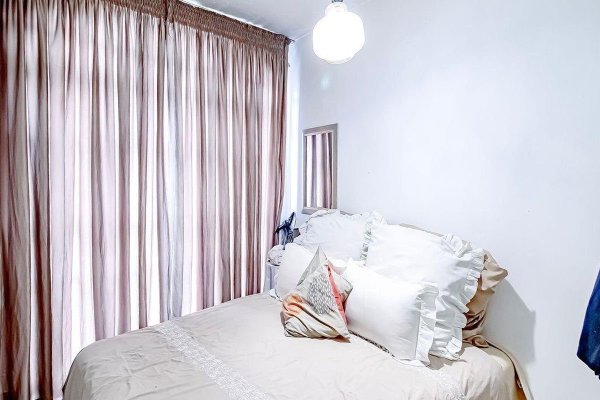 A compact bedroom featuring floor-to-ceiling curtains and a central light fixture, providing a functional and private sleeping space.