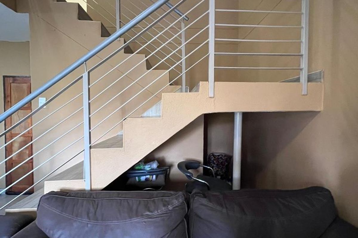 Interior view of a living area featuring a staircase with a modern metal balustrade and neutral wall tones.