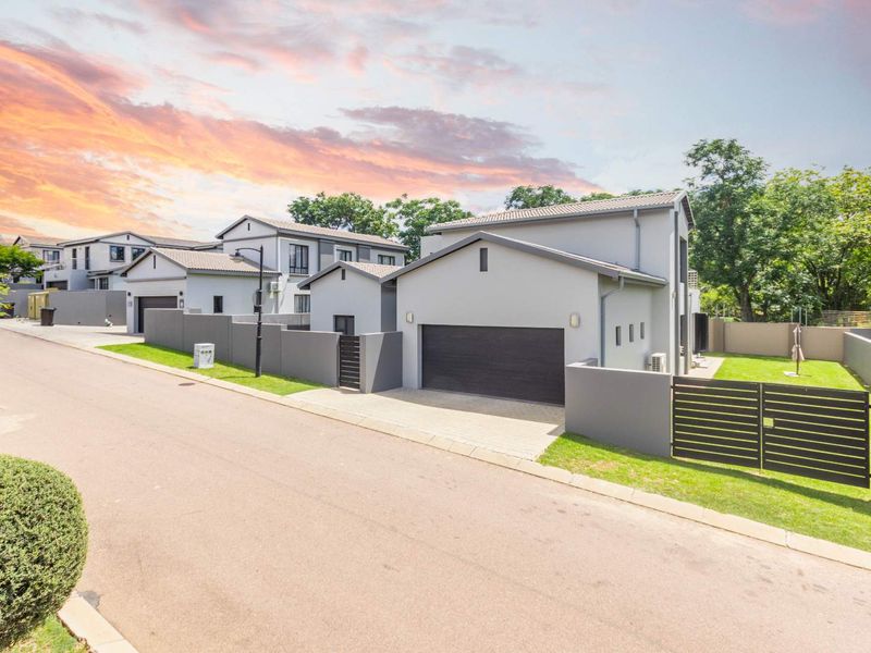 Modern residential property featuring a double garage, paved driveway, and secure boundary walling in a well-maintained estate setting.