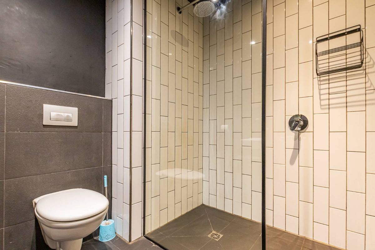 Modern bathroom featuring a walk-in shower with glass enclosure, subway tile surround, and a wall-mounted toilet with concealed cistern.
