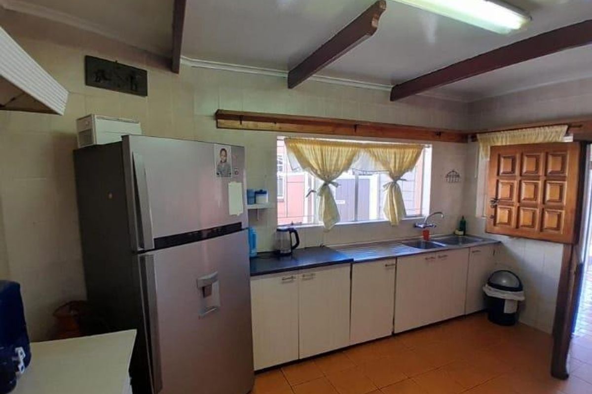 A functional kitchen featuring built-in cabinetry, a double sink, and exposed ceiling beams, offering a dated aesthetic with potential for modernization.