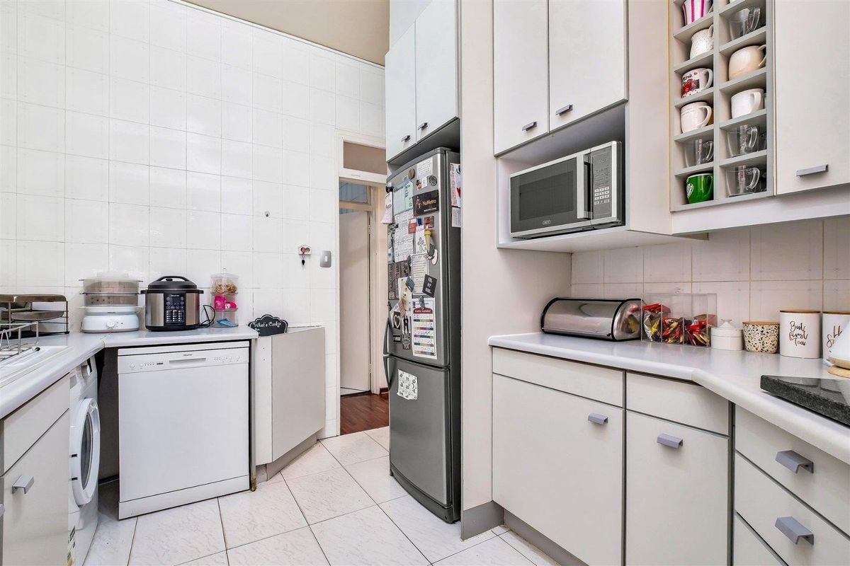 Functional kitchen featuring white cabinetry, tiled walls, built-in microwave, and dedicated space for a dishwasher and laundry appliances.